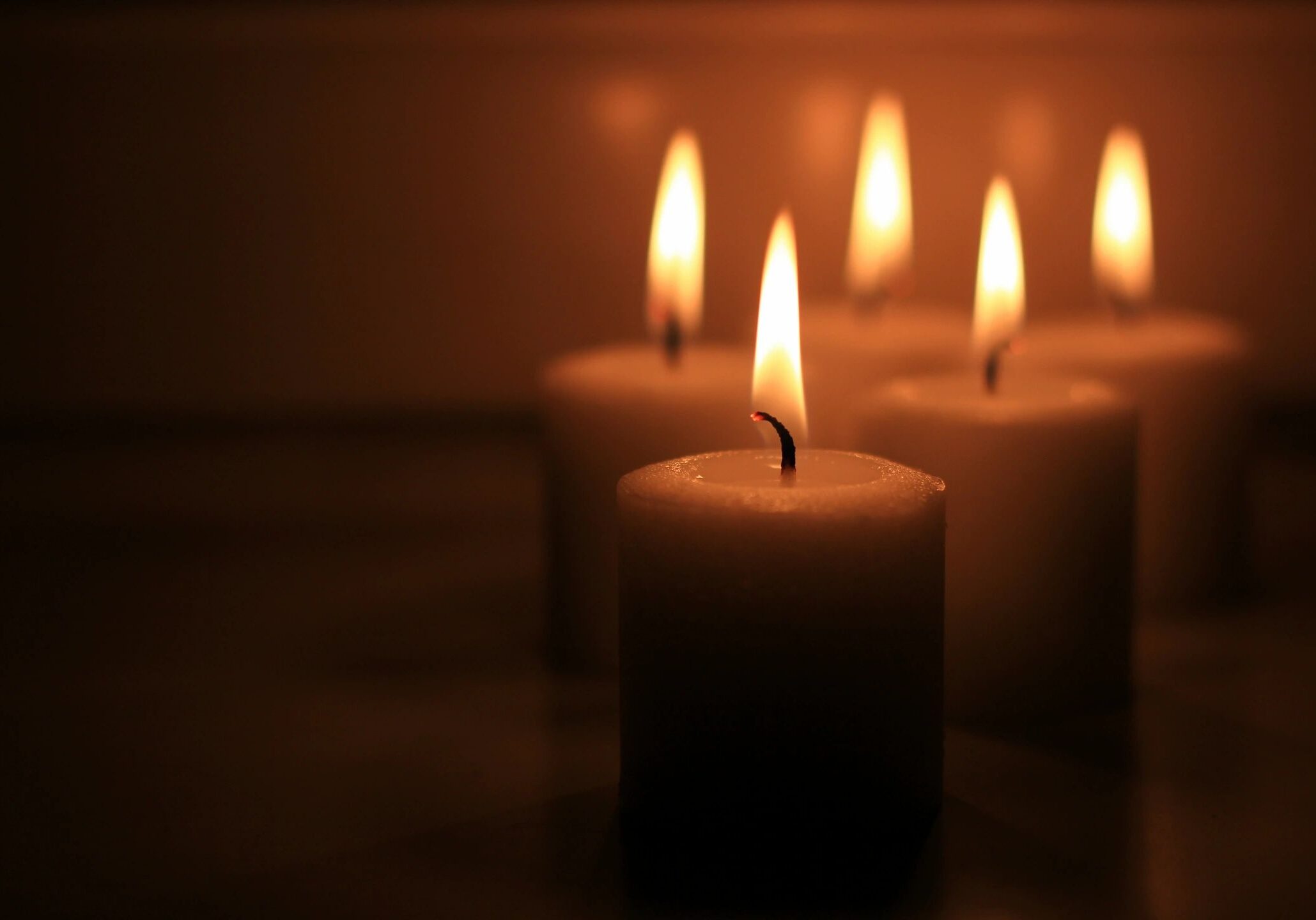 Five lit candles in a dark setting.