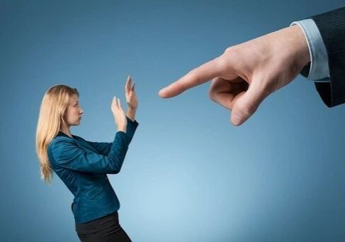 Person intimidated by a large pointing finger.