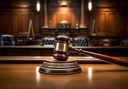 Gavel in empty courtroom on wooden desk.