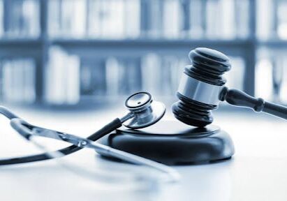 Gavel and stethoscope on desk, blurred background.