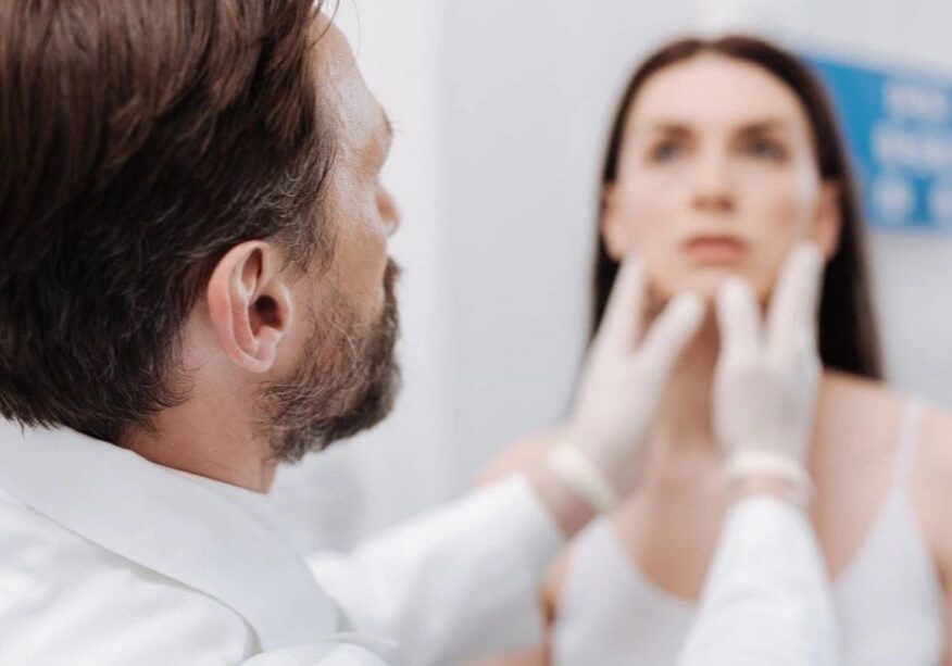 Doctor examining patient's face in clinic.