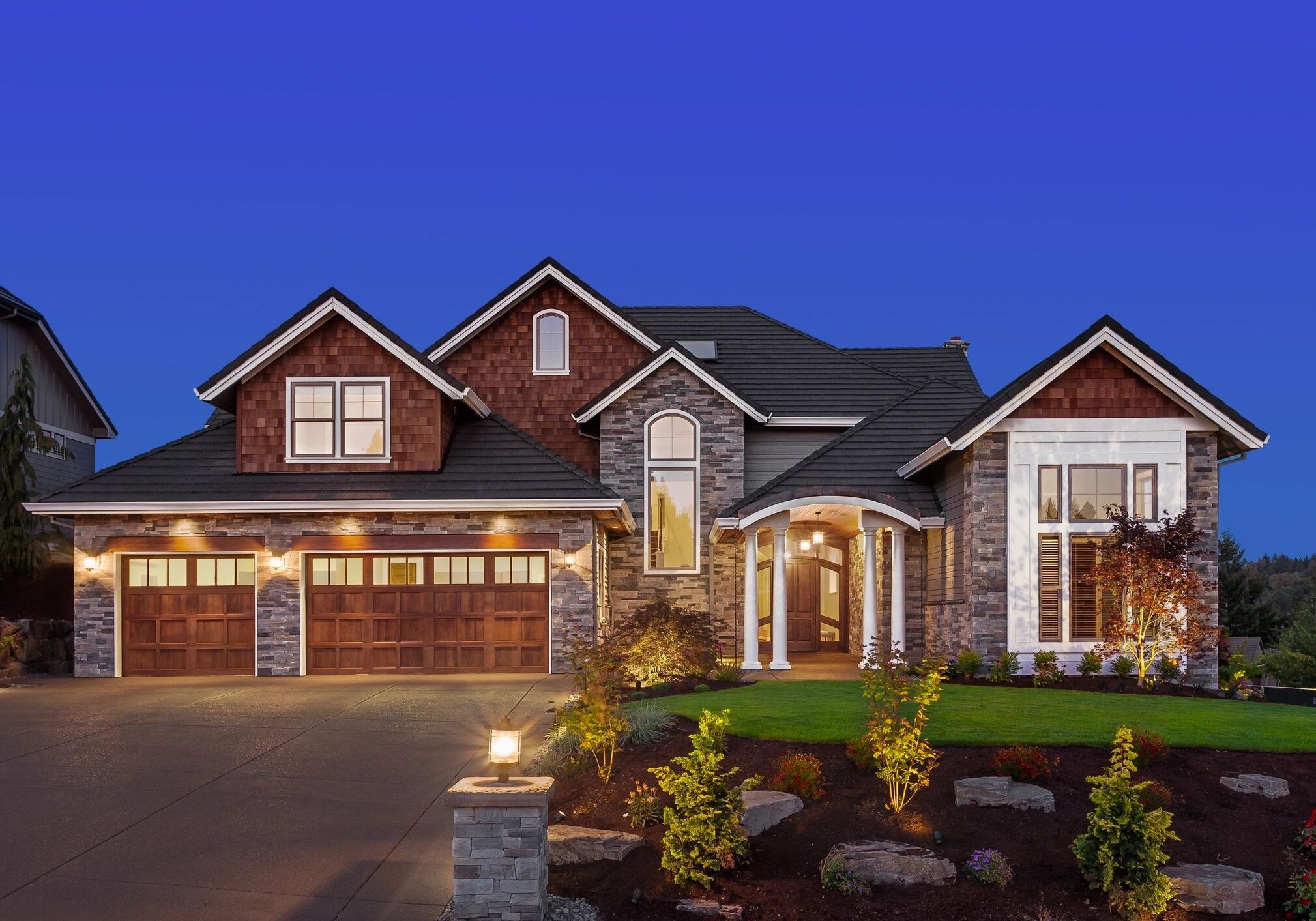 Modern house with landscaped front yard at dusk.