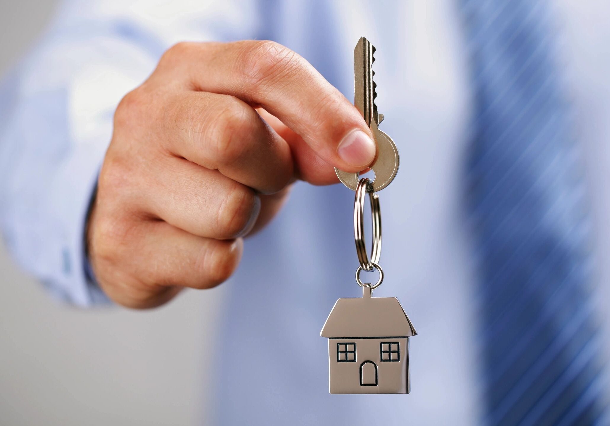 Hand holding house key with keychain.