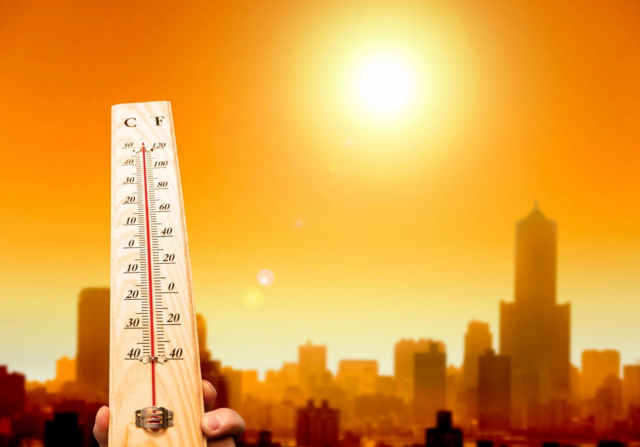 Thermometer with hot city skyline background.
