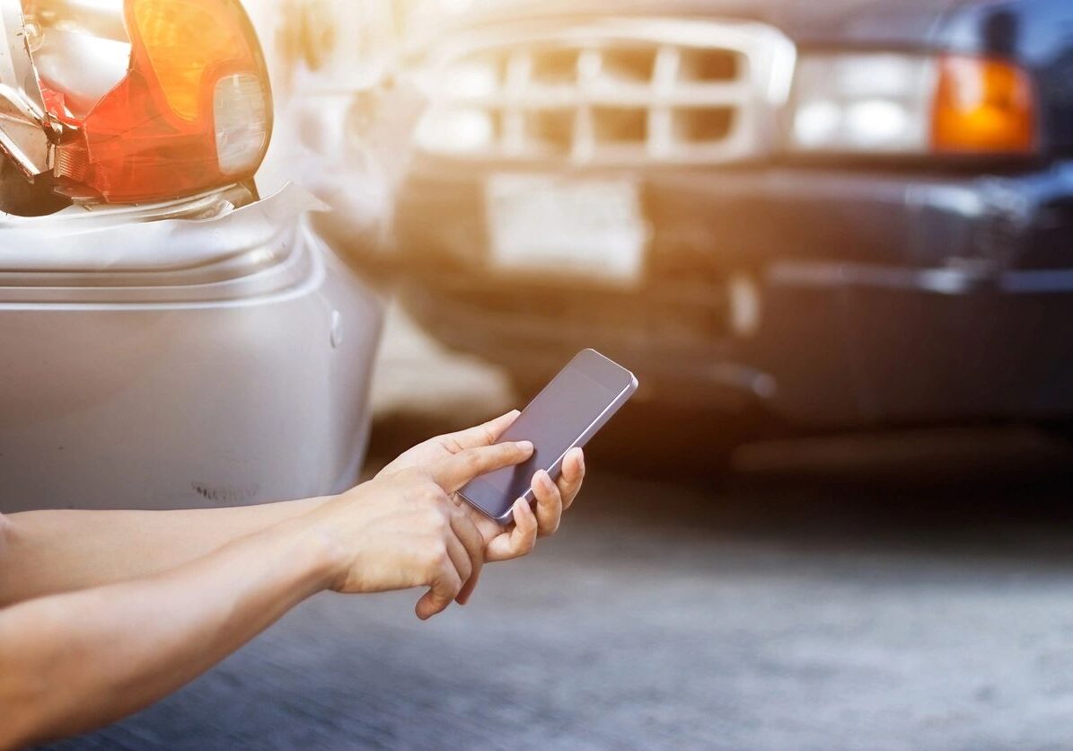Person photographing car accident with smartphone.