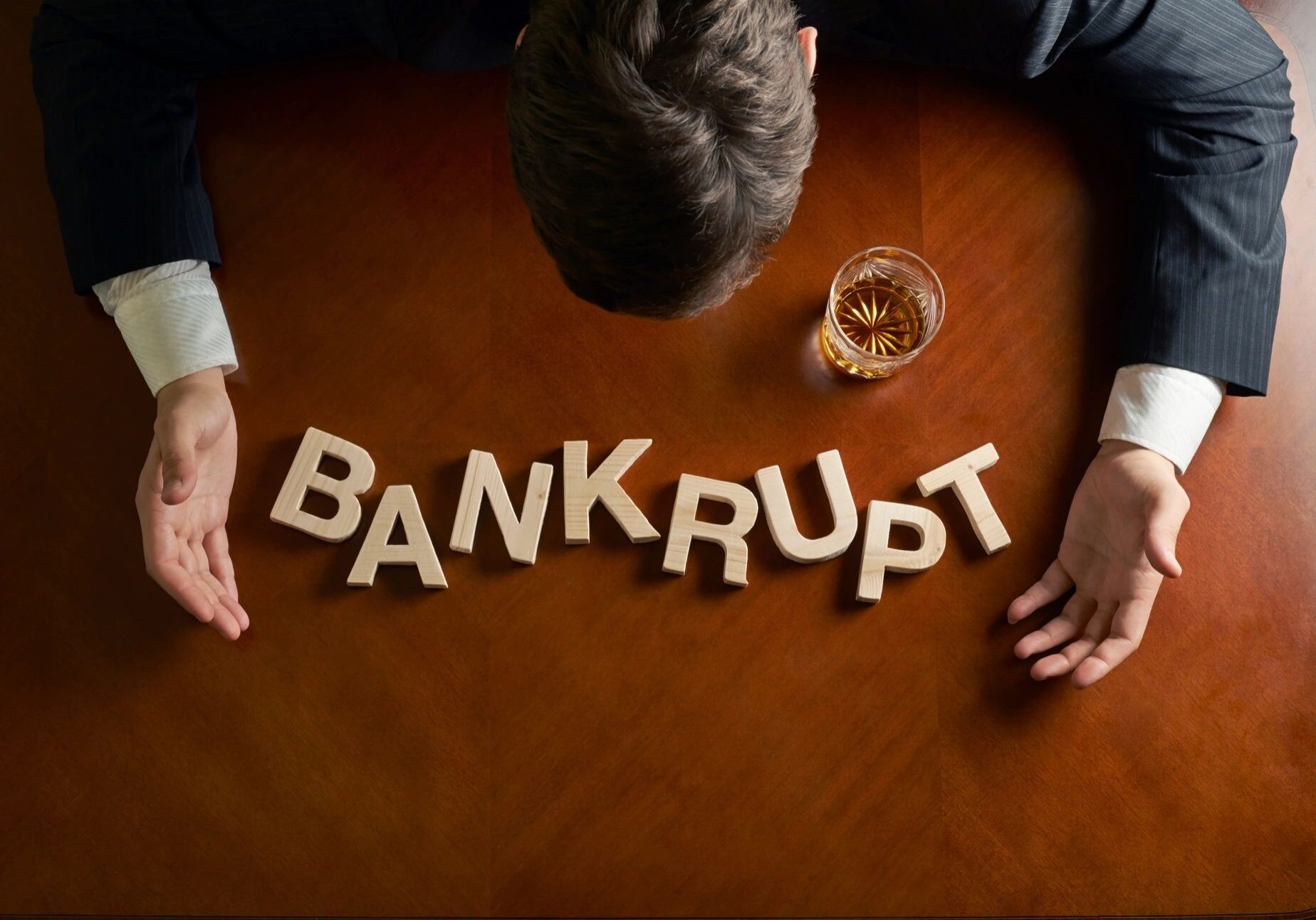 Man with "bankrupt" letters and drink.