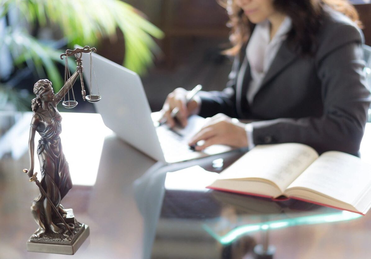 Lawyer working on laptop with legal statue.