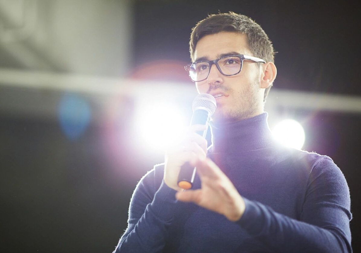 Man speaking into microphone on stage.