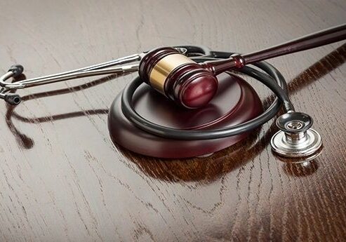 Gavel and stethoscope on wooden table.