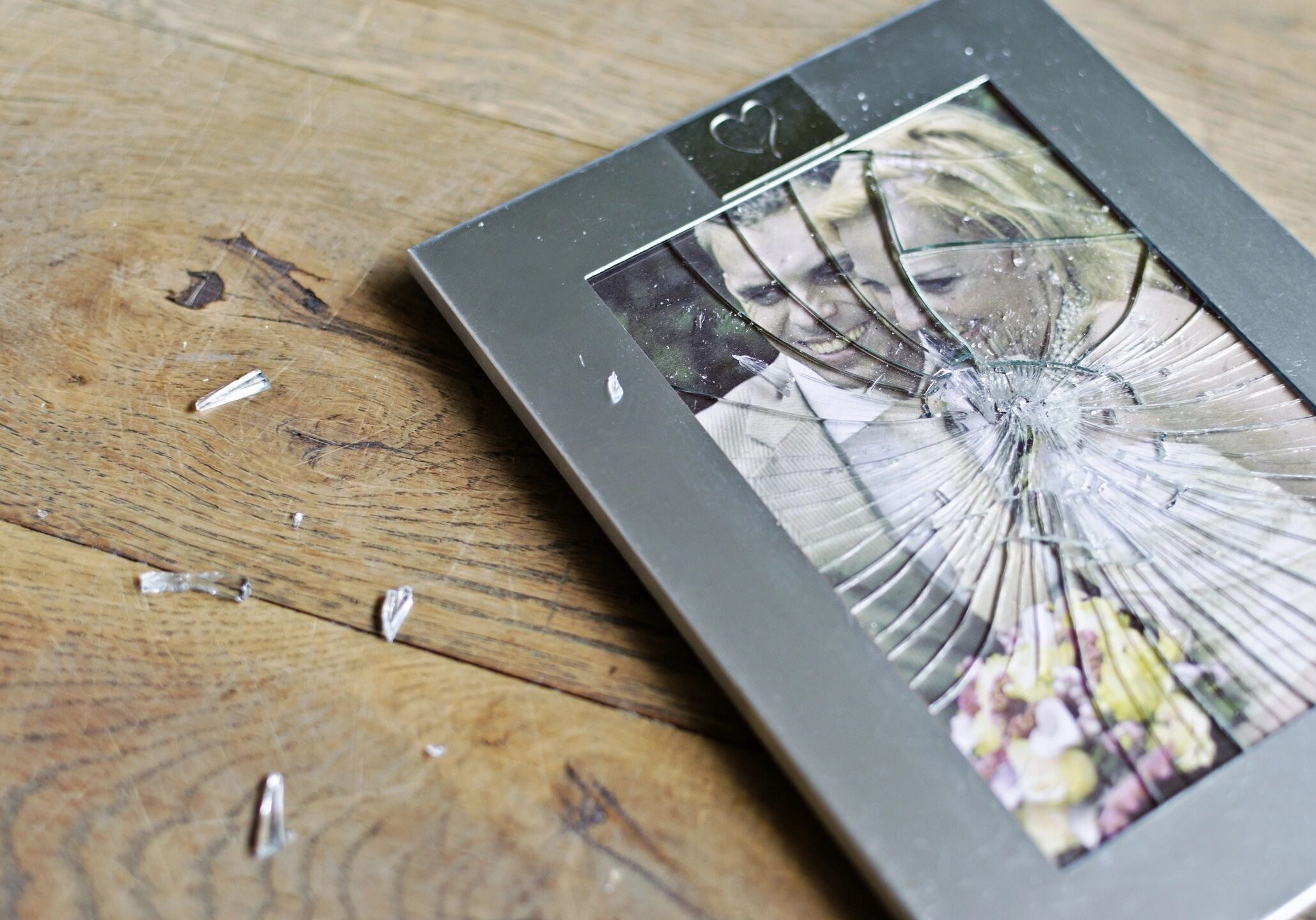 Broken glass photo frame on wooden floor.
