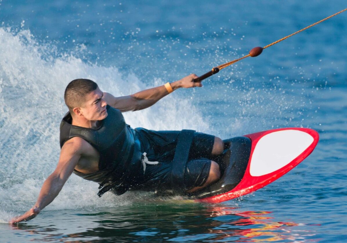 Man kneeboarding on water with rope.