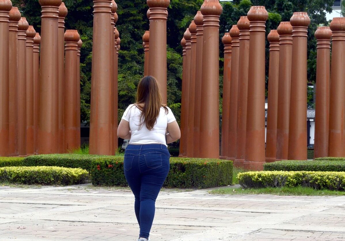 Woman walking near tall brown columns.