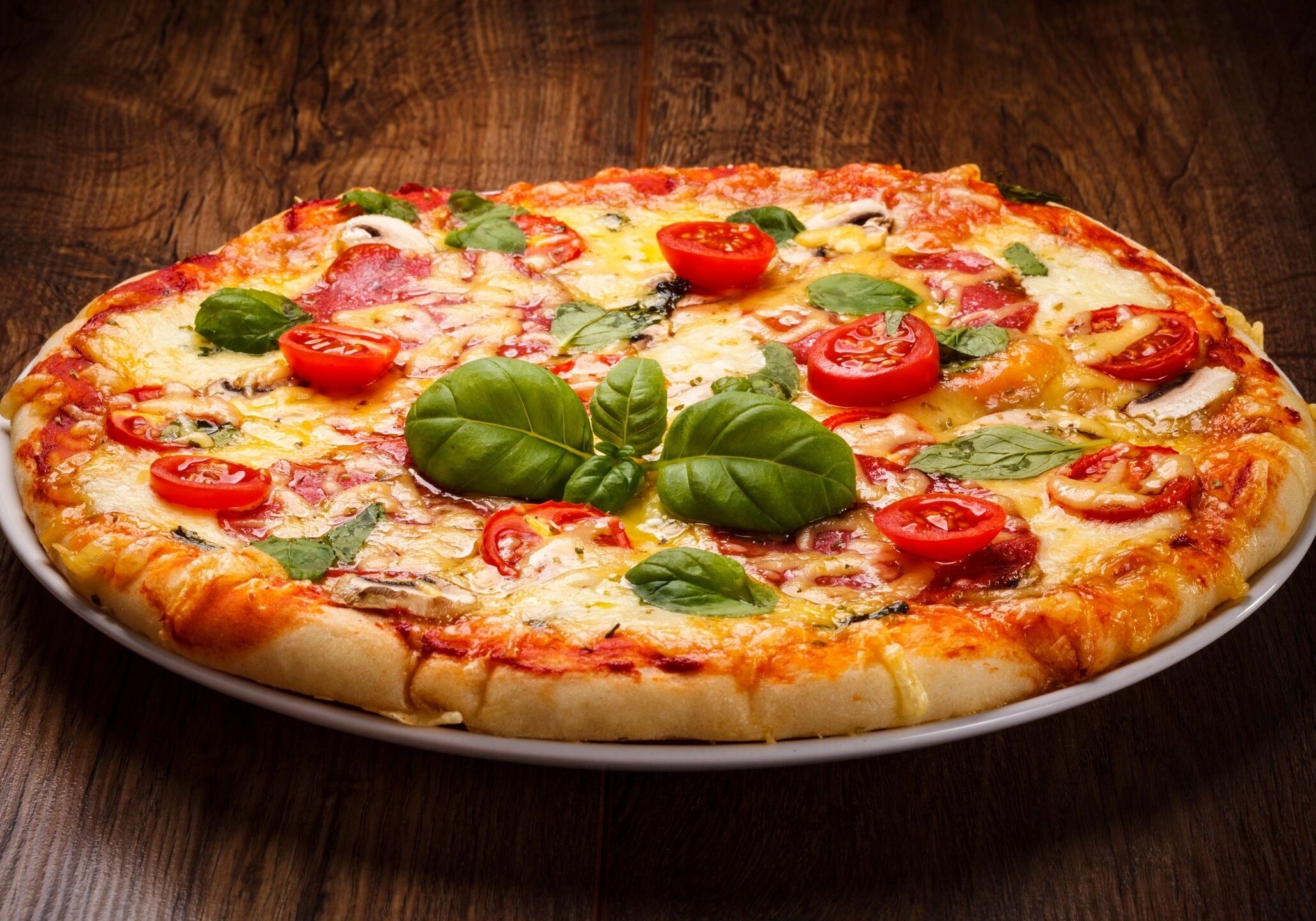 Pizza with tomatoes and basil on plate.