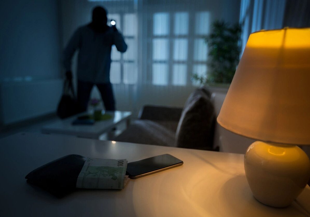 Burglar in dimly lit room with lamp.