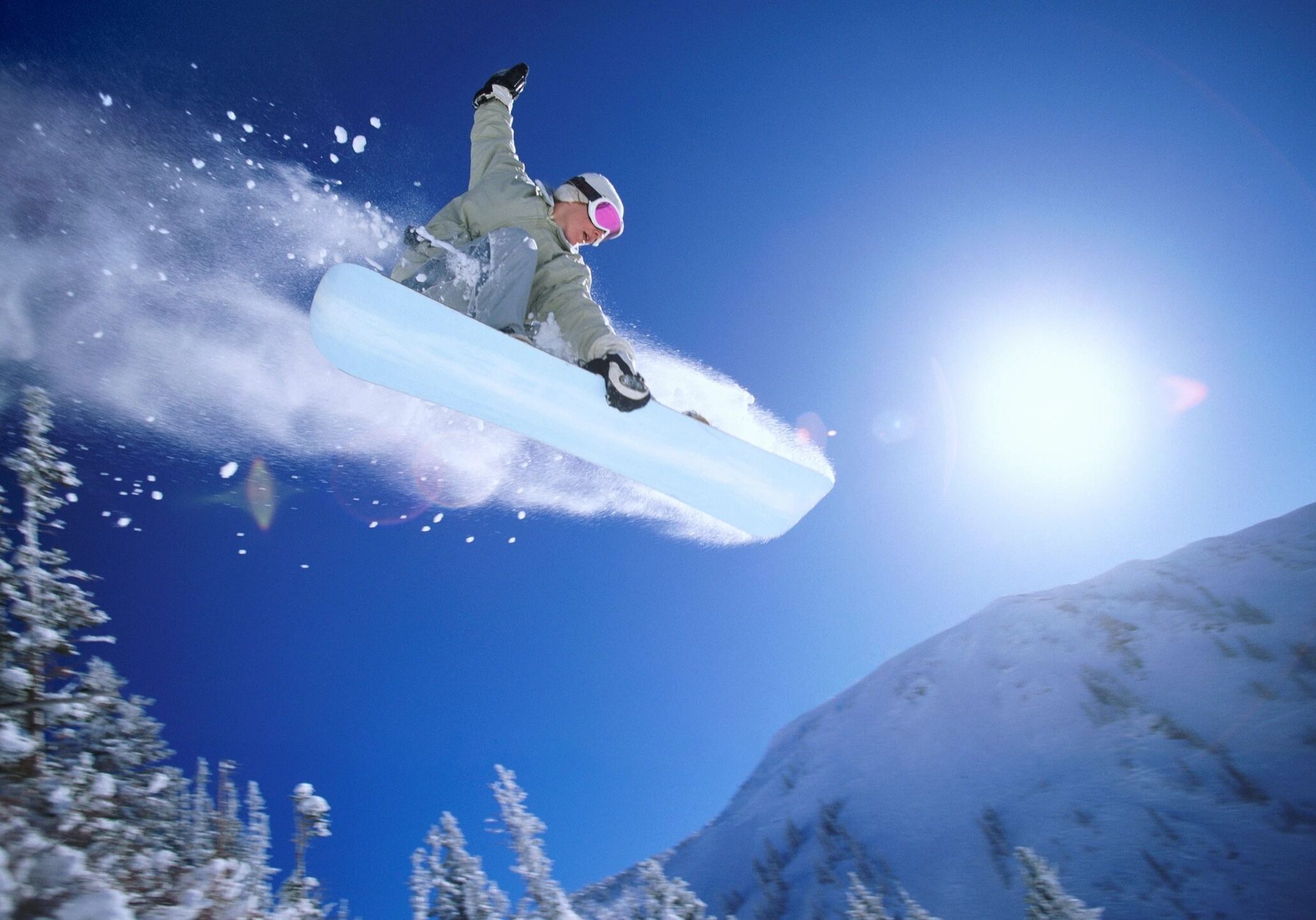 Snowboarder jumping high in snowy mountains.