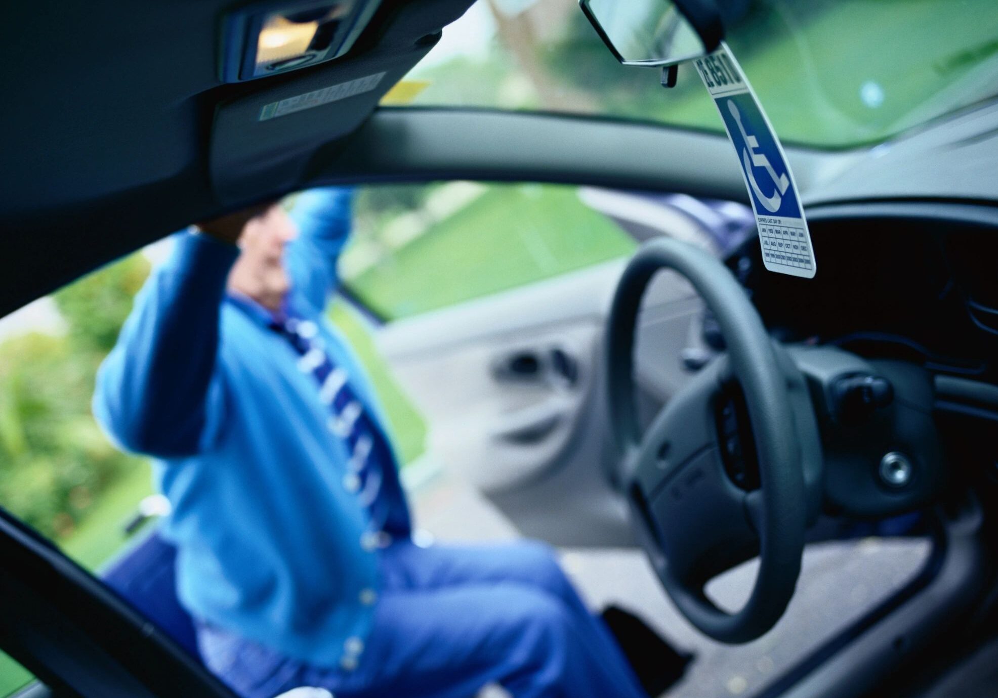 Person entering car with disability permit visible.