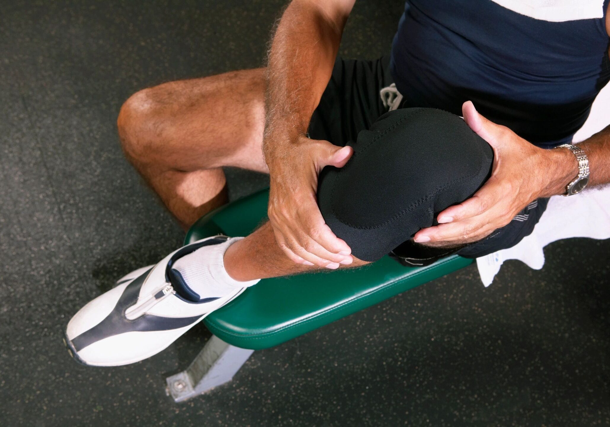 Man holding knee on exercise bench.