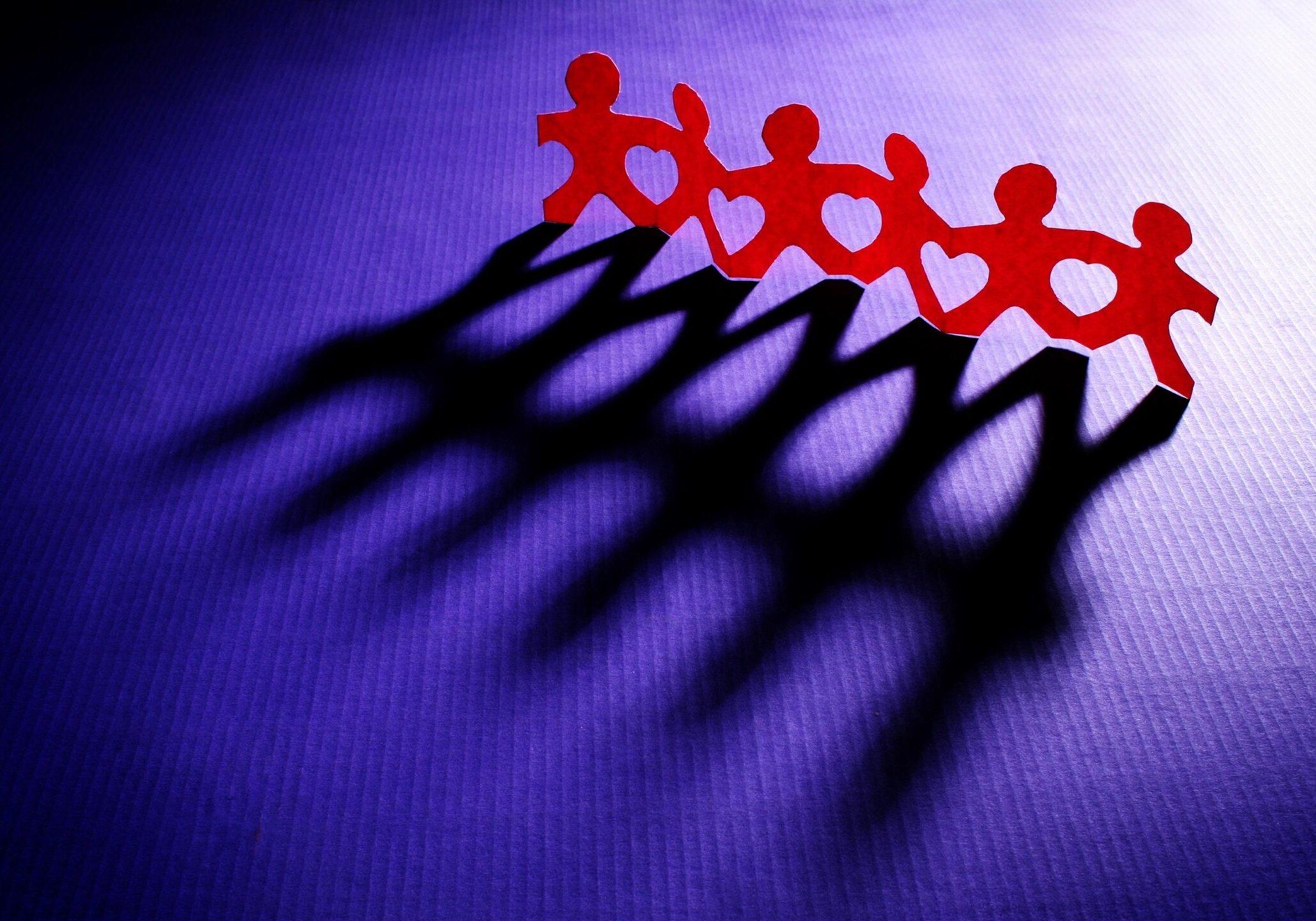 Paper chain figures casting dramatic shadows.