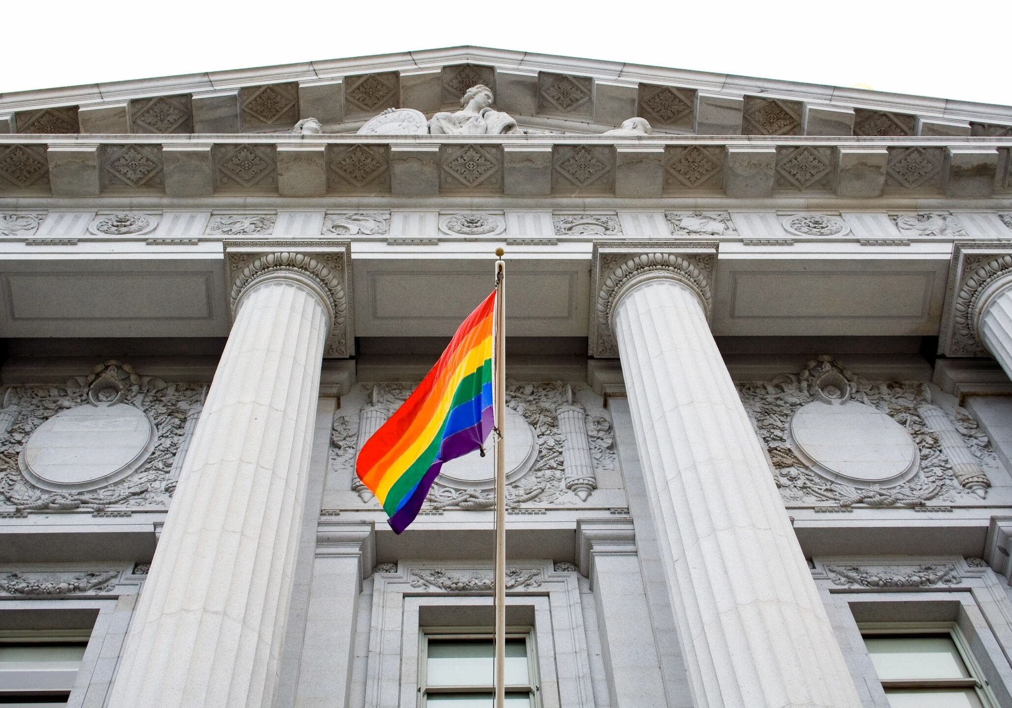 Rainbow flag outside government building with columns.