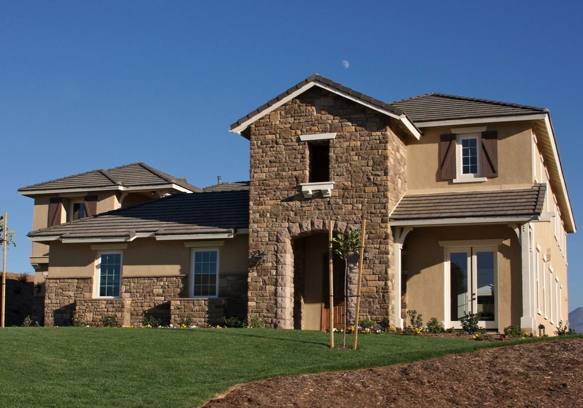 Modern stone house with green lawn.