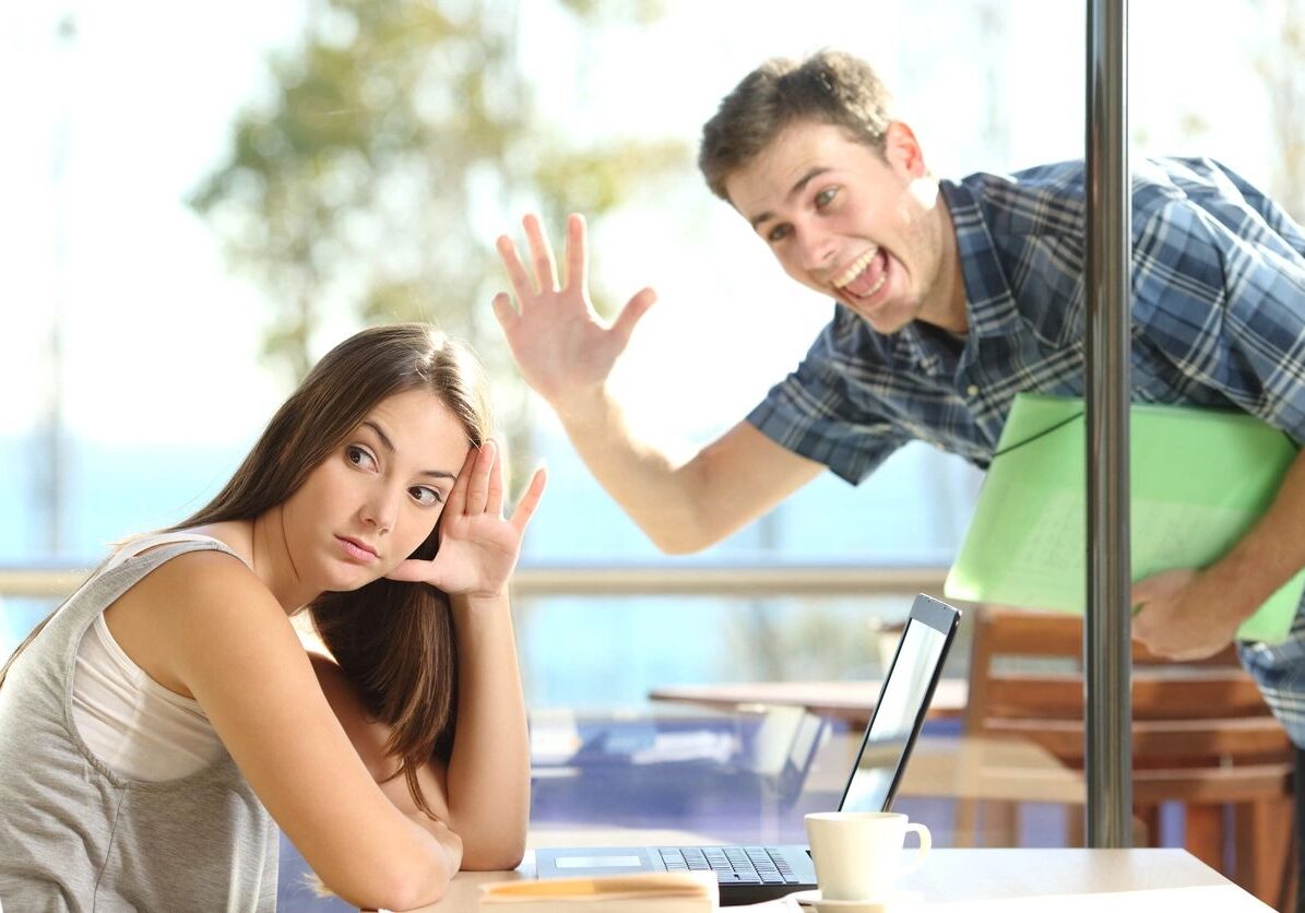 Man waving at uninterested woman in café.