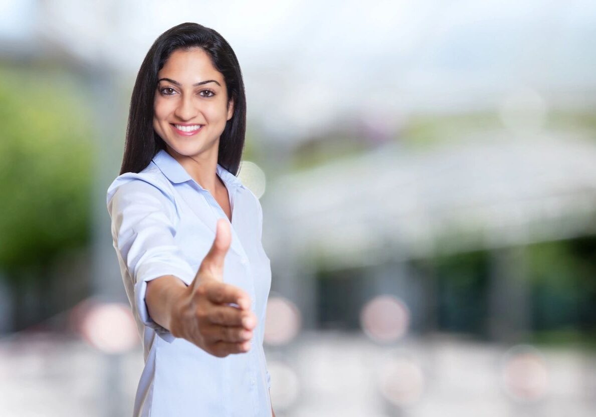 Smiling woman extending hand for handshake.